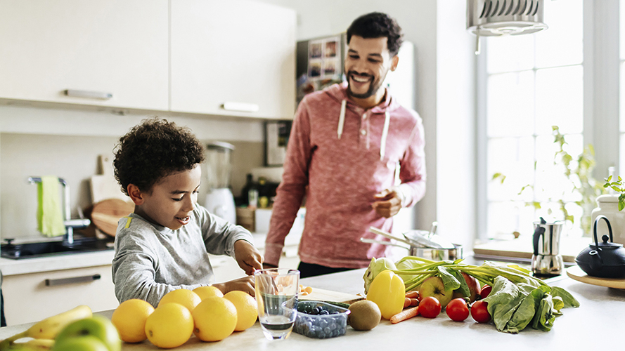 Un niño y su padre en la cocina. Preparan alimentos saludables con verduras. 