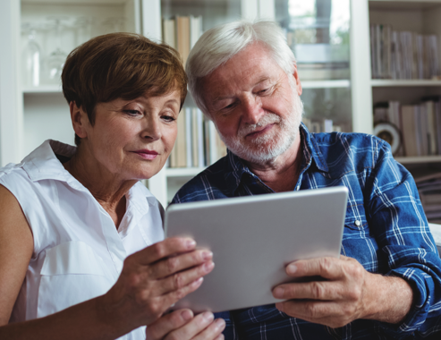 Un hombre y una mujer mayores mirando una tablet PC.