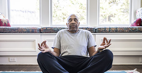 Hombre adulto mayor está meditando en casa