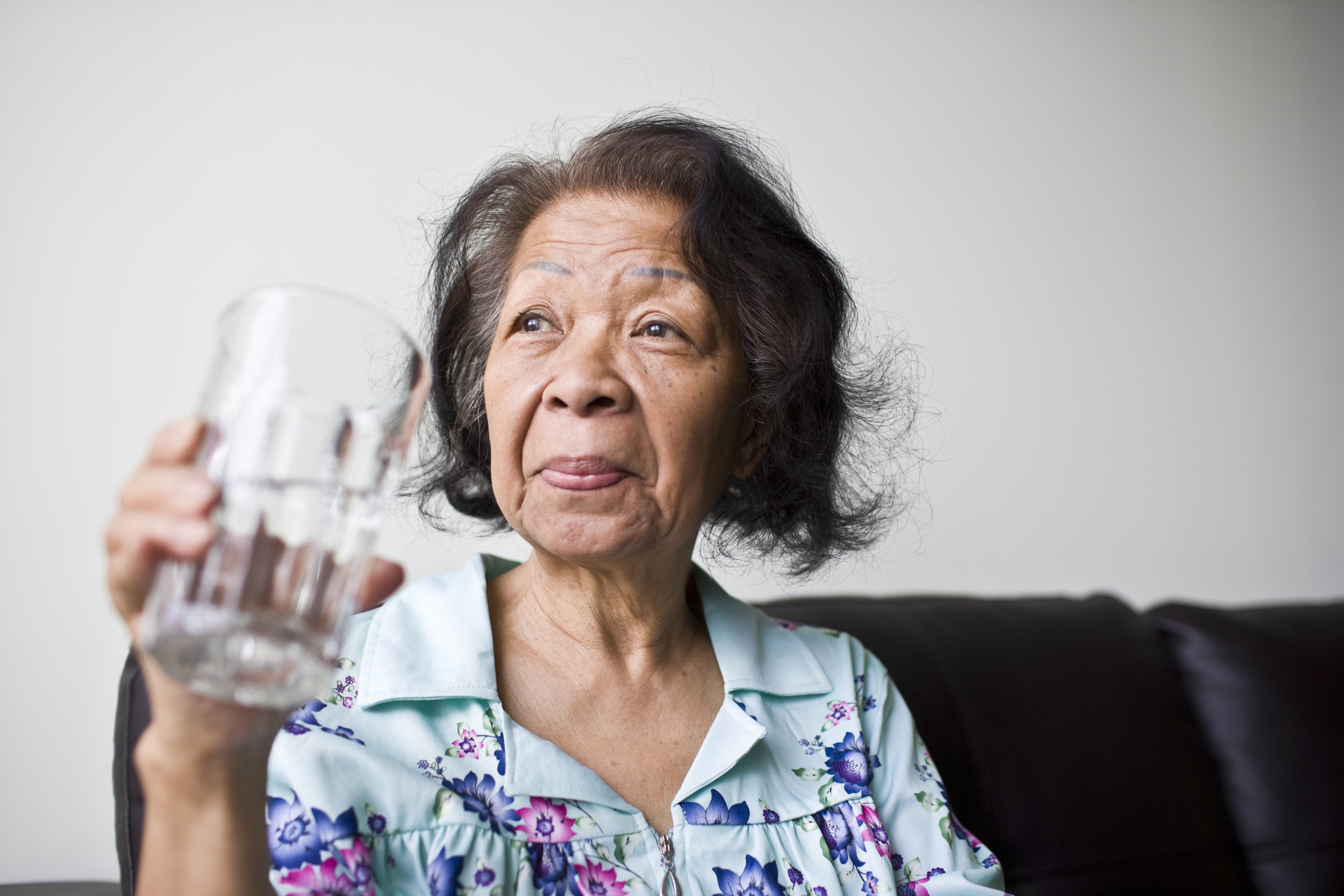 Mujer asiática adulta madura con un vaso de agua refrescante