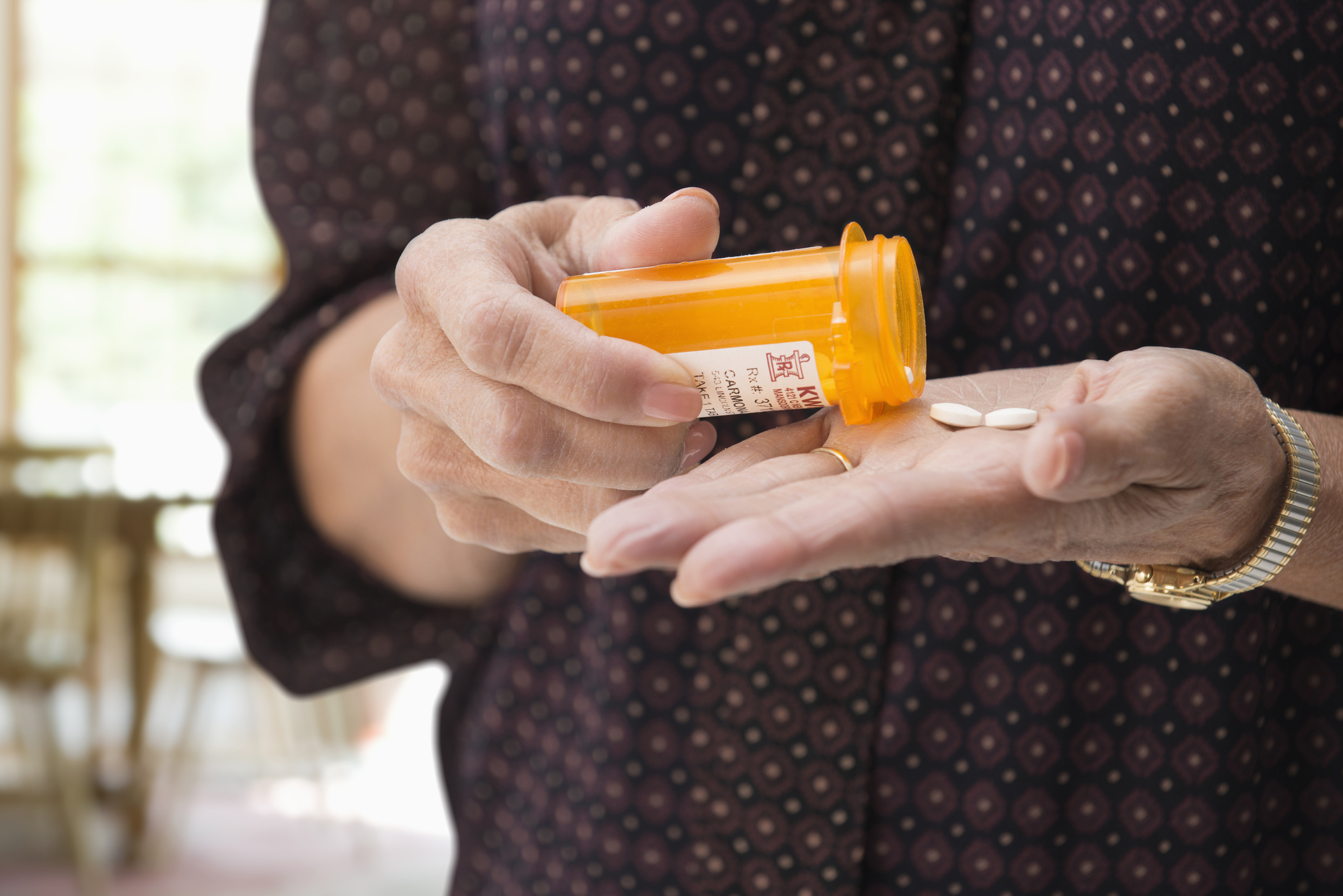 Mujer de raza mixta sosteniendo pastillas de medicación