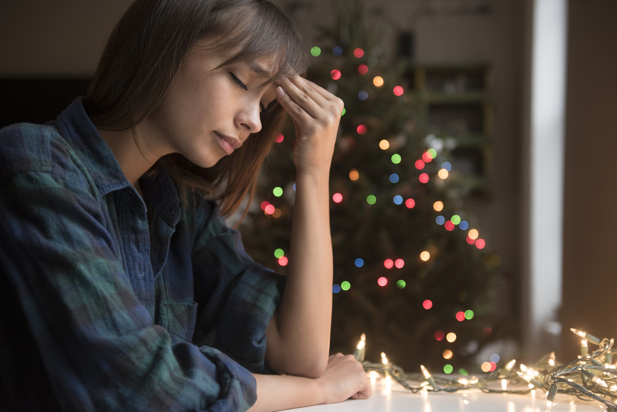 Mujer con dolor de cabeza cerca de un árbol de Navidad