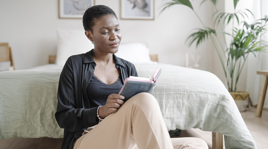 Woman enjoying read a book while relaxing at home. Hobbies and literature concept.