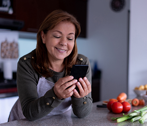persona sonriendo y enviando mensajes de texto a su asesor de salud en la cocina