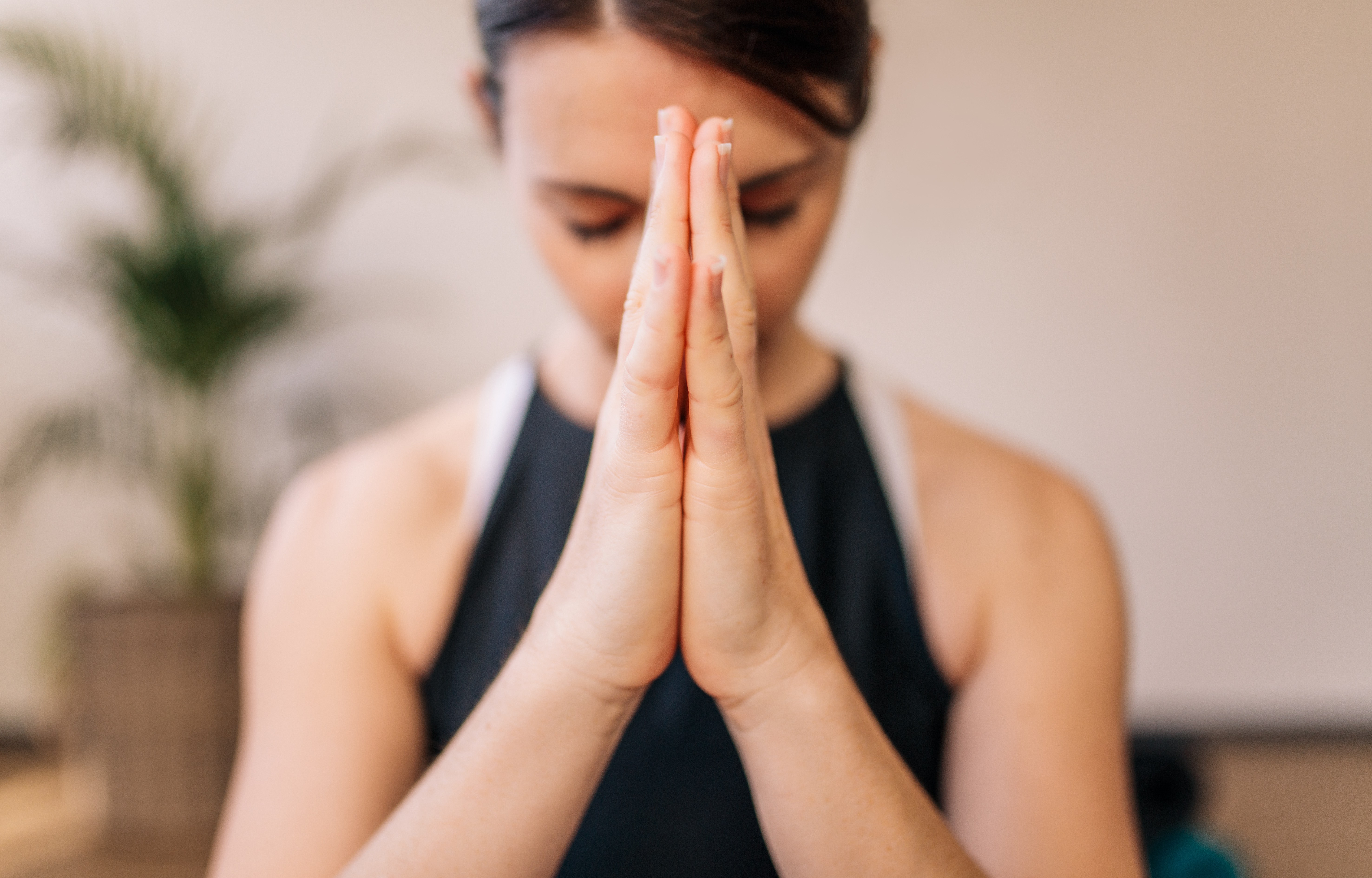 Primer plano de manos de mujeres unidas. Mujer meditando con las manos unidas en un ambiente interior. Postura de namaste yoga, meditando, respirando y relajándose.