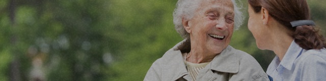 Older woman outside, smiling with her daughter.