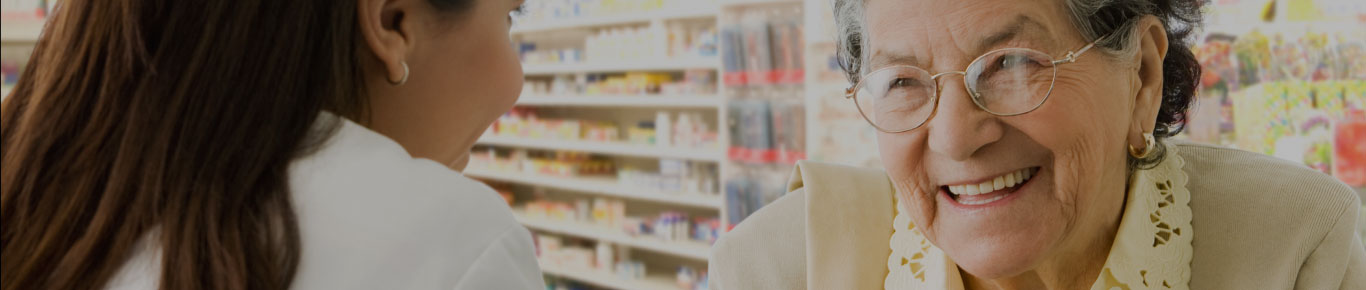 Mujer mayor con gafas sonriendo a un farmacéutico.