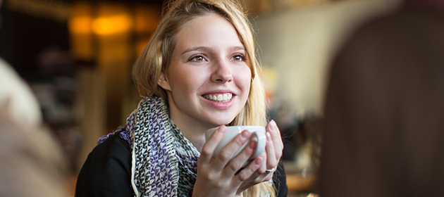 mujer adulta joven tomando café y sonriendo