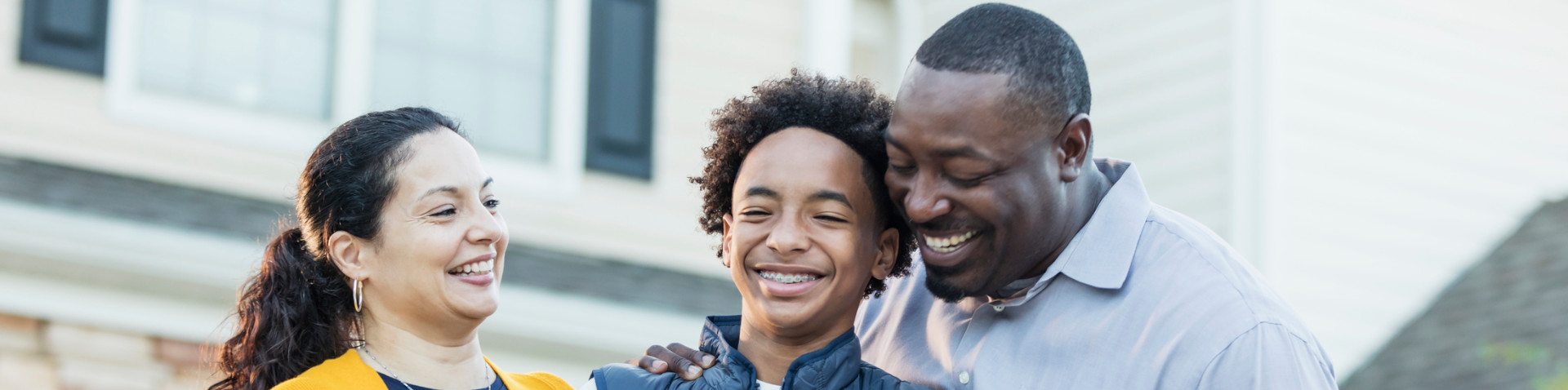 Una familia de dos adultos y un niño sonriendo