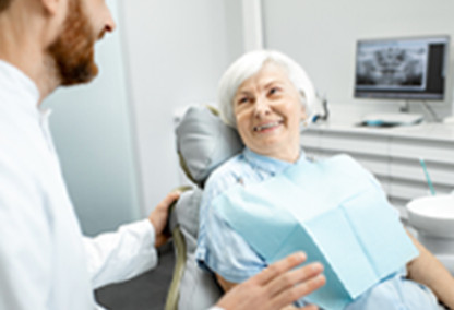 Mujer mayor sonriendo sobre un sillón de dentista