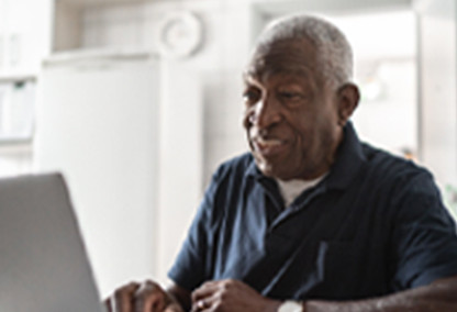 Hombre mayor sonriendo en su computadora